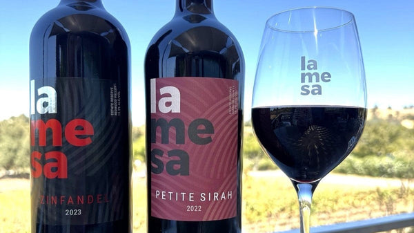 La Mesa Zinfandel 2023 and Petite Sirah 2022 next to red wine glass on the sunny vineyard patio terrace 
