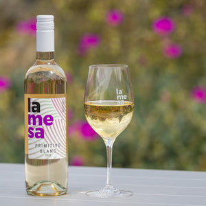 Primitivo Blanc 2025 with blurred flowers behind