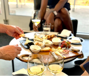 People enjoying a charcuterie with wine at an indoor table at the La Mesa weekend bistro.
