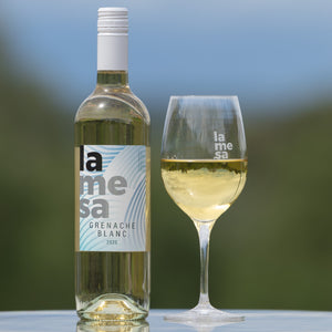 Bottle and glass of La Mesa Grenache Blanc wine with a blurred background