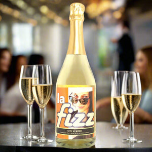 Bottle of La Fizz Almond sparkling wine with two glasses on a table in a social setting.