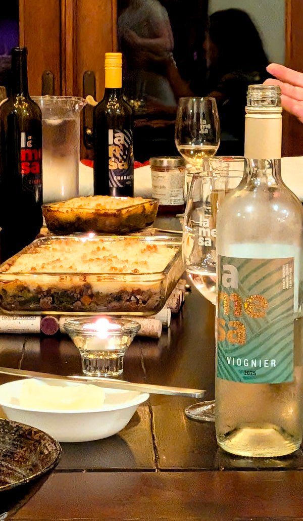 Table set with a mix of dishes, La Mesa wines in the foreground and background